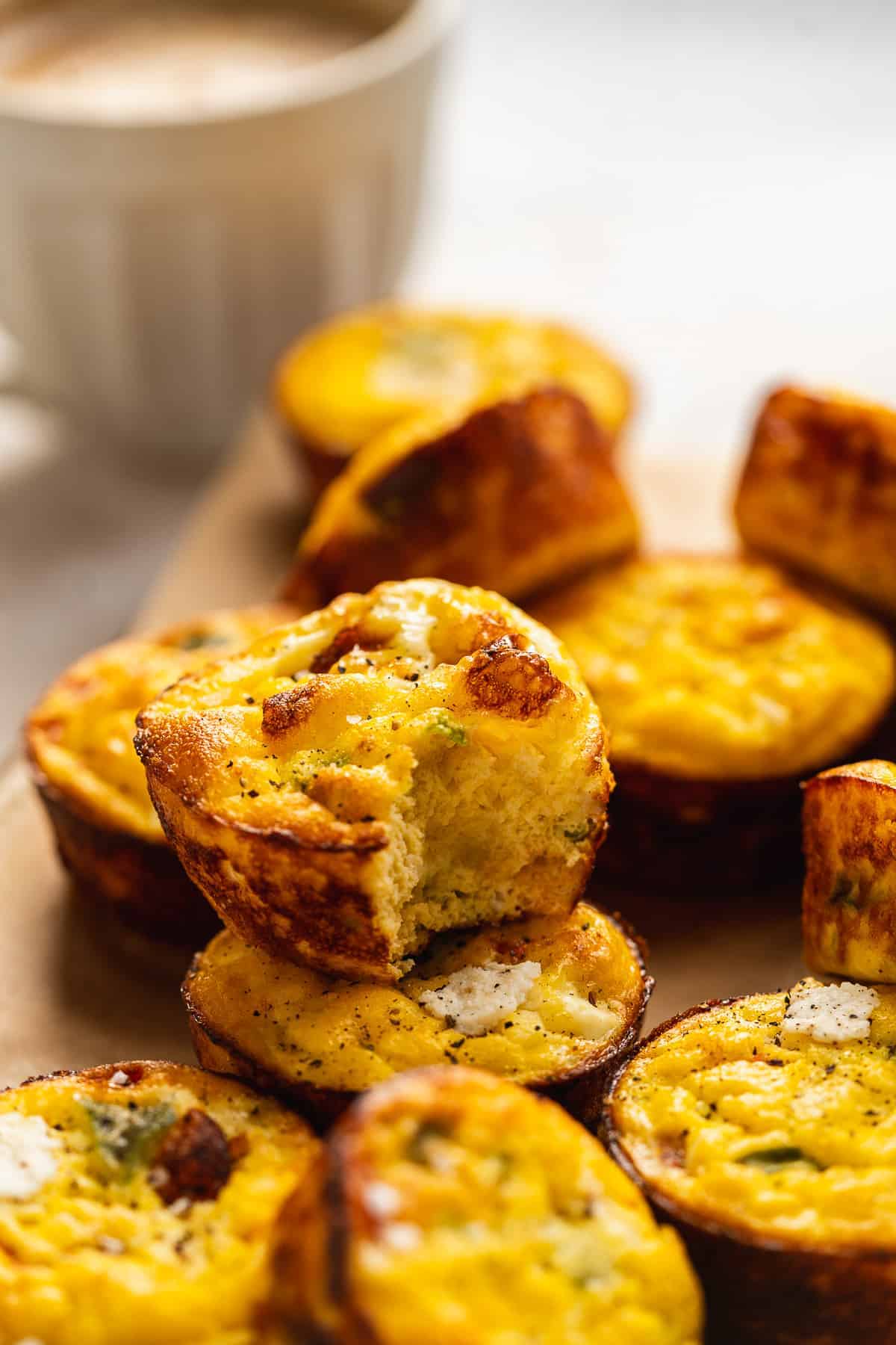 Pile of ricotta egg bites on a surface with a bite taken out of one.