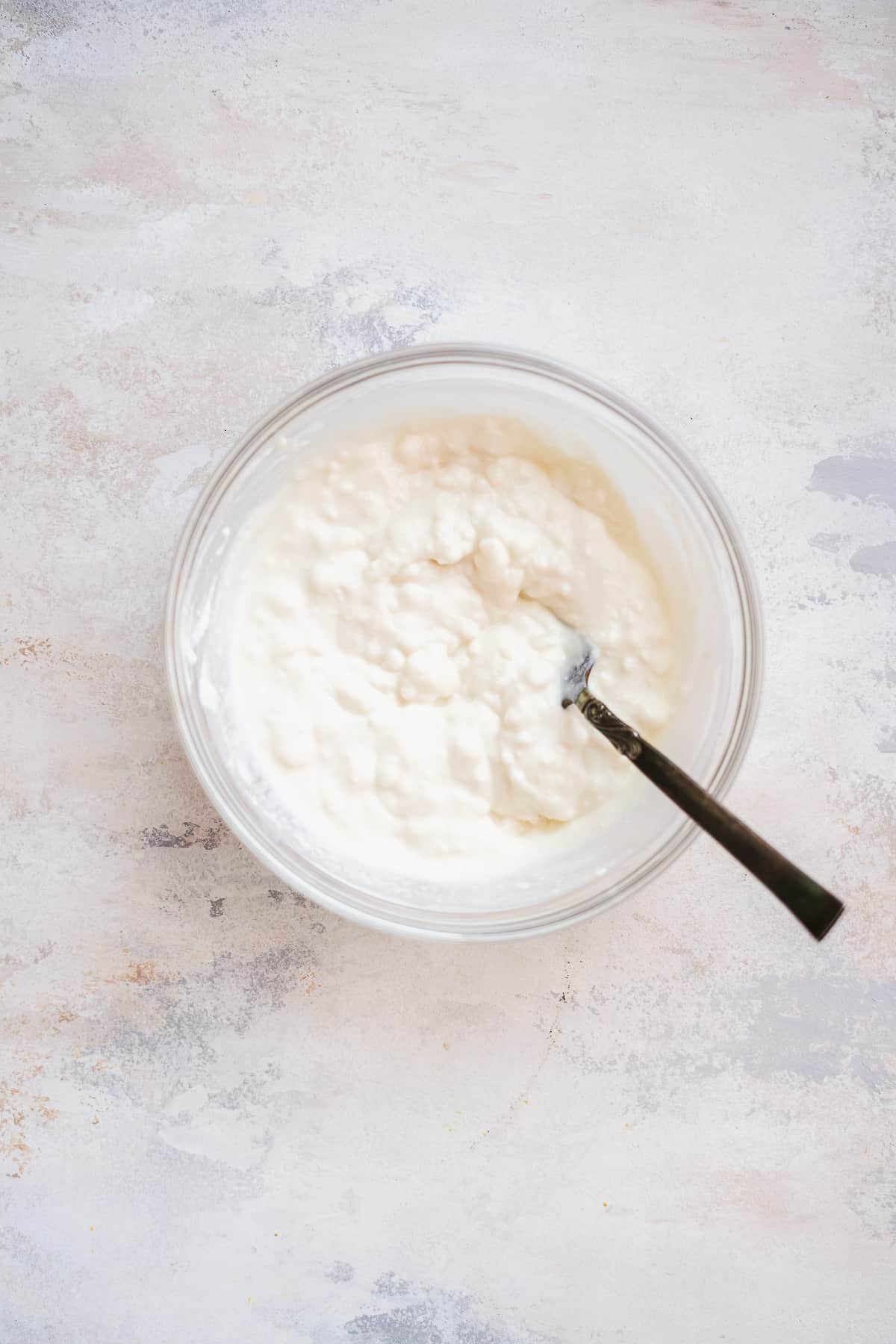 Bowl with creamy ricotta and a fork inside on a blue surface.