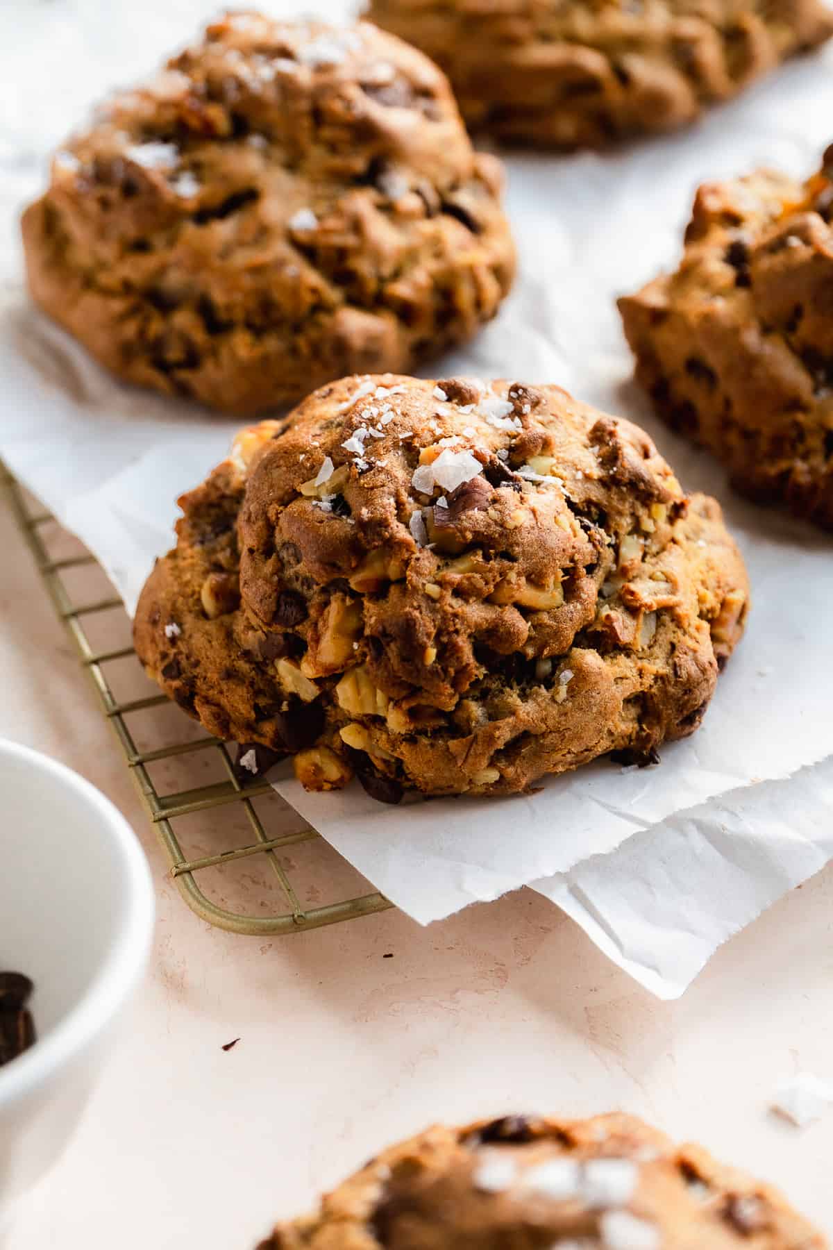Chunky bakery style cookies on a cooling rack with parchment paper.
