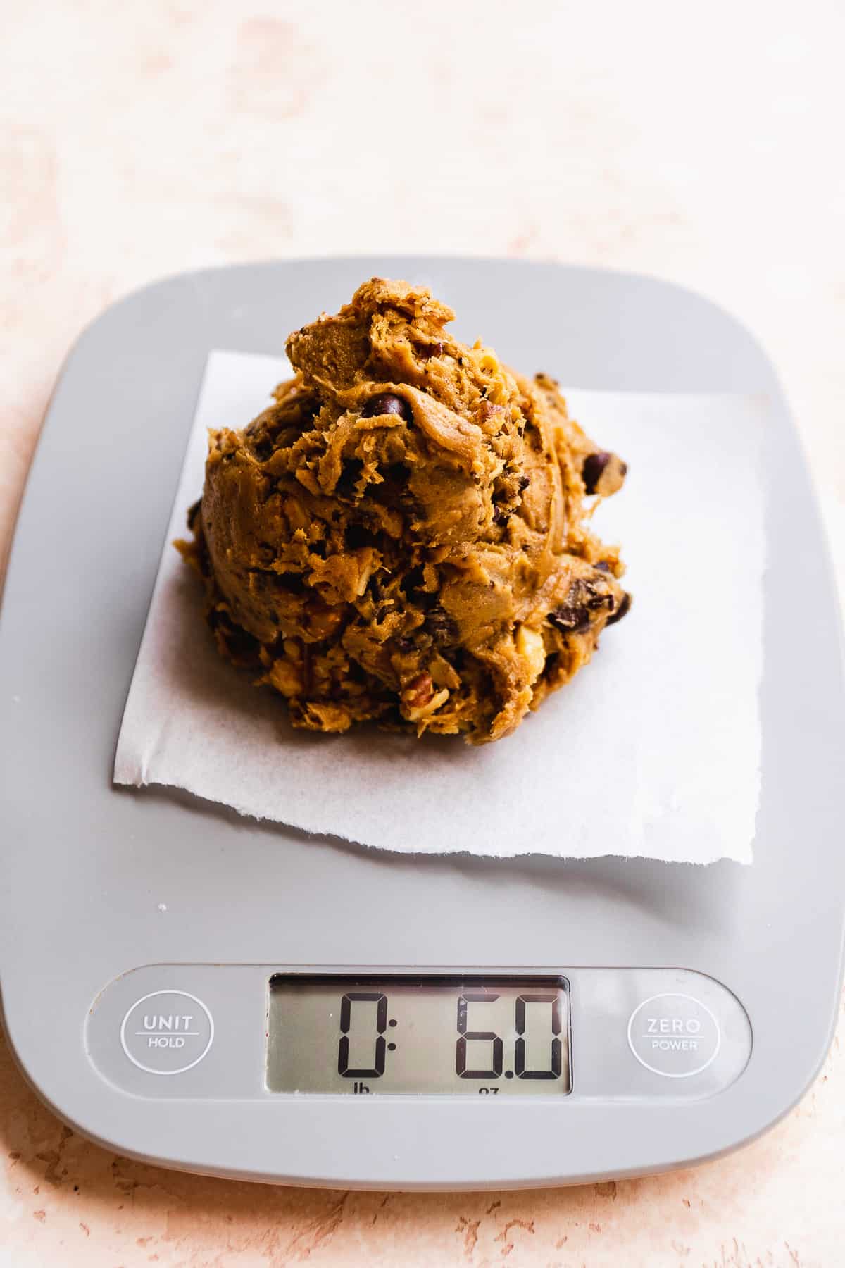 Cookie dough being weighed on a kitchen scale.