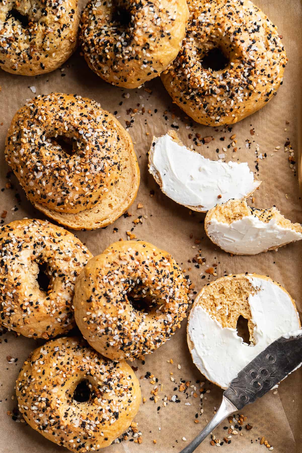 Gluten free everything bagels scatter on a baking sheet.