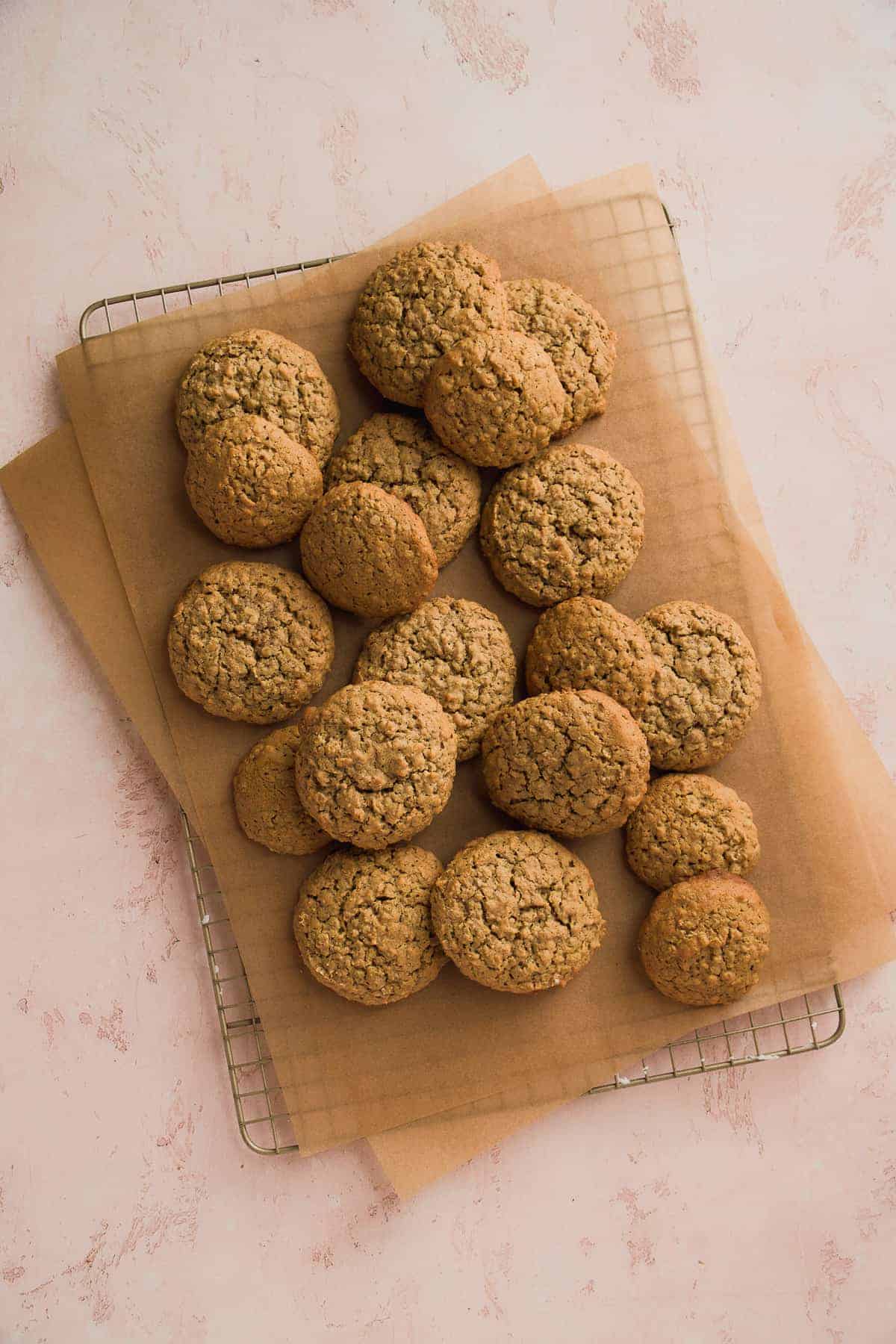 Wire cookie rack with parchment paper and oatmeal cookies scattered on top.