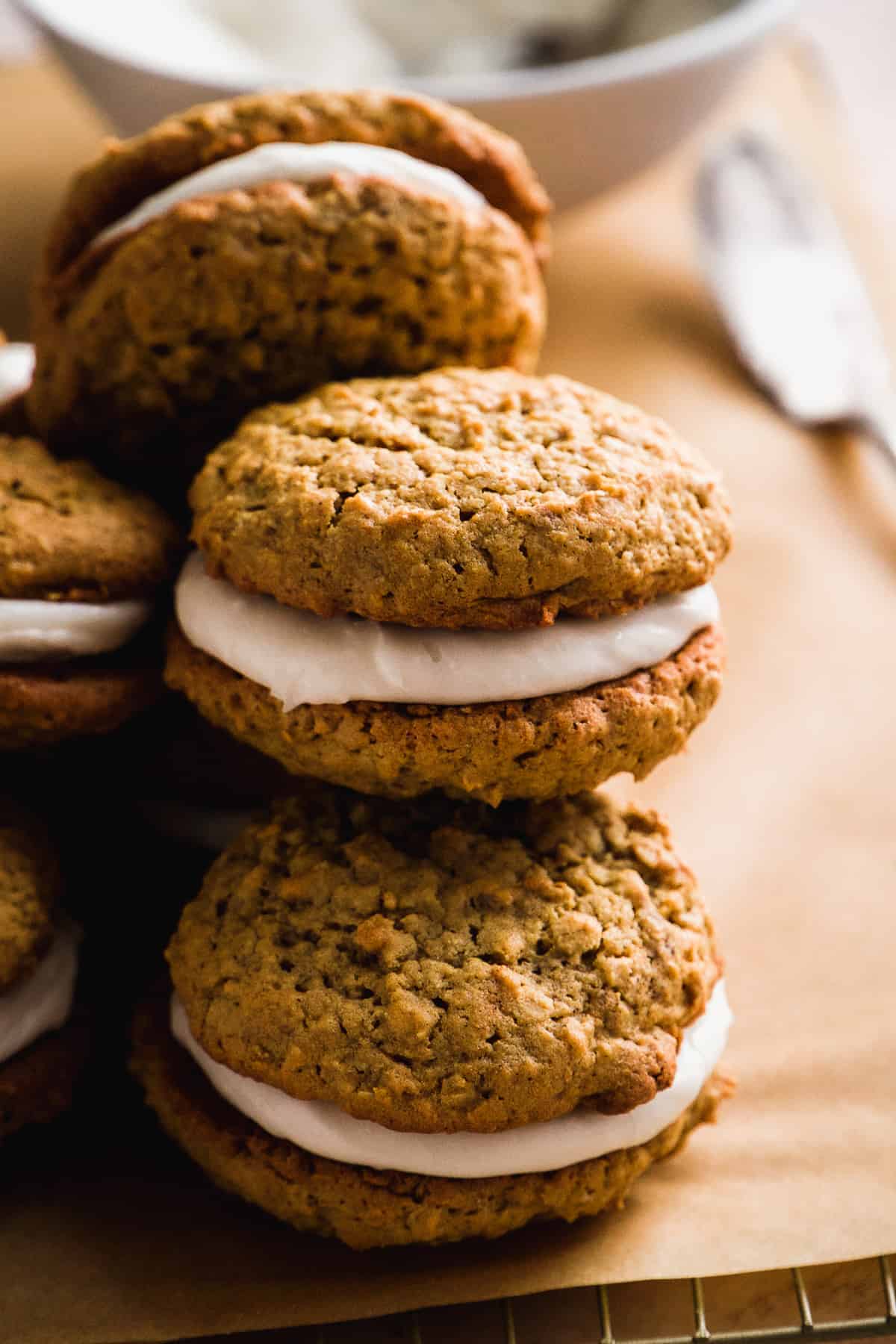 Gluten free oatmeal cream pies stacked on top of one another on a wire cooling rack.