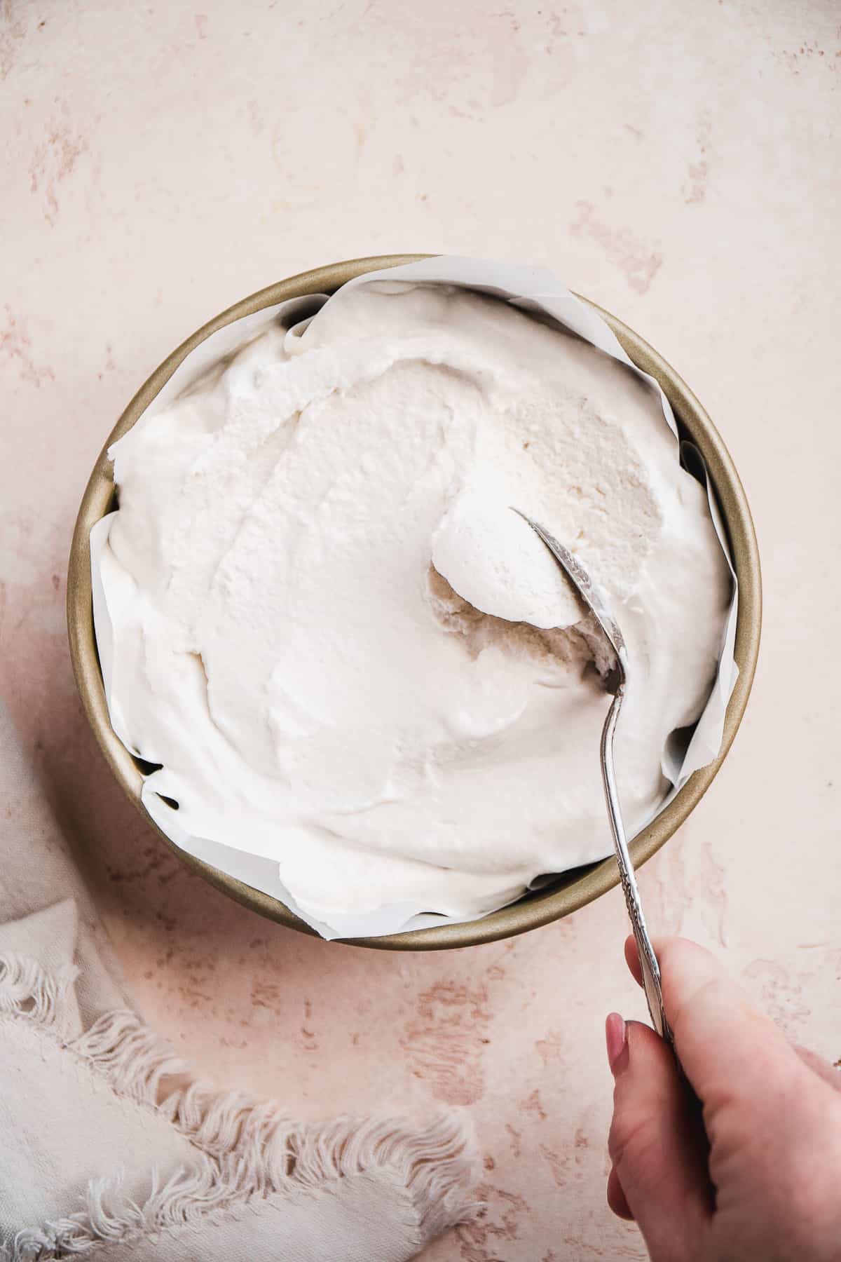 Container with coconut milk ice cream and a hand taking a spoonful out.