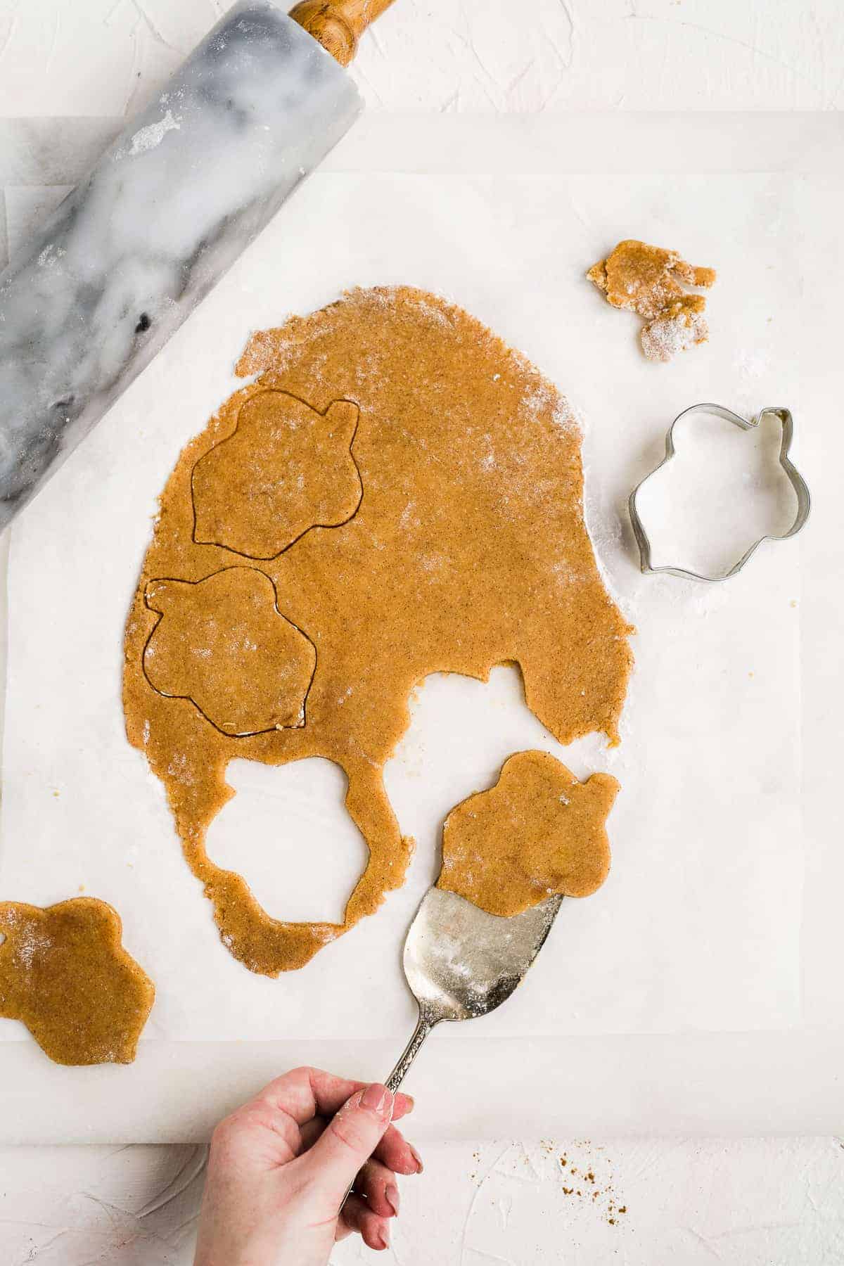 Overhead photo of almond flour peanut butter cookies being cut out with a cookie cutter.