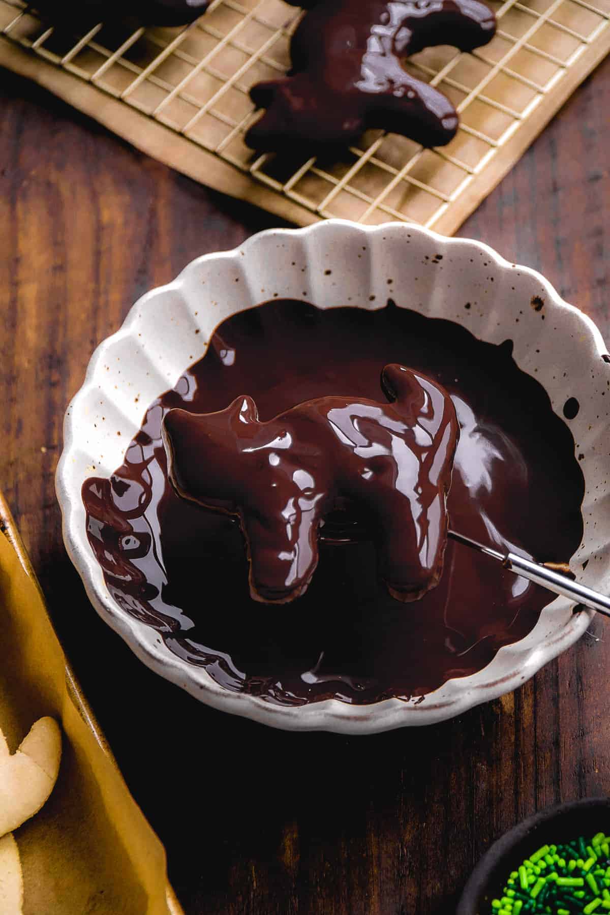 Cat shaped cookie being dunked in a bowl of melted chocolate.