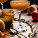 Caramel apple martini on a gold platter with black background.