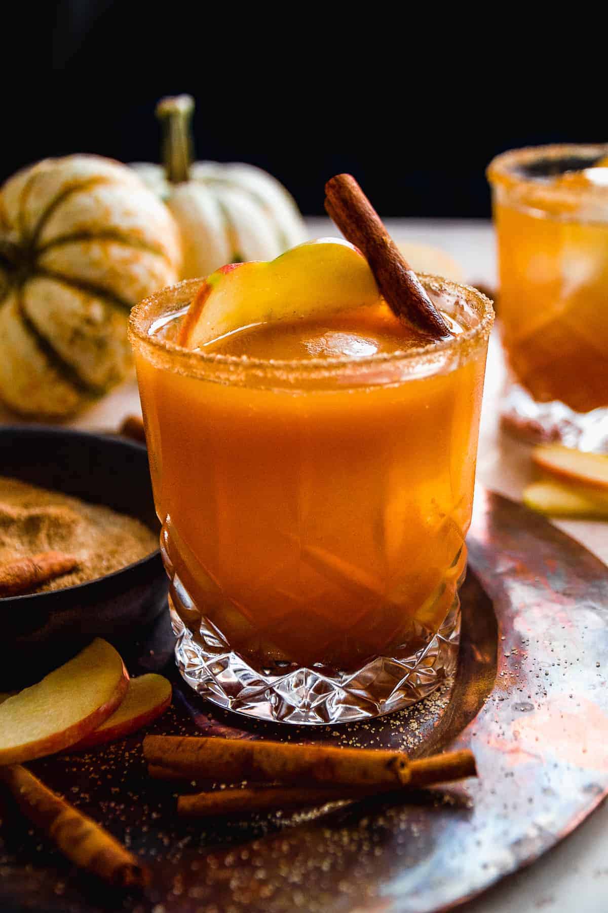 Pumpkin apple cider cocktail on a copper platter with cinnamon stick inside.