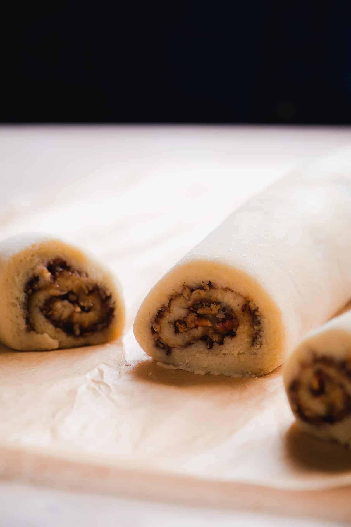 Cinnamon roll log on parchment paper in front of a black background.