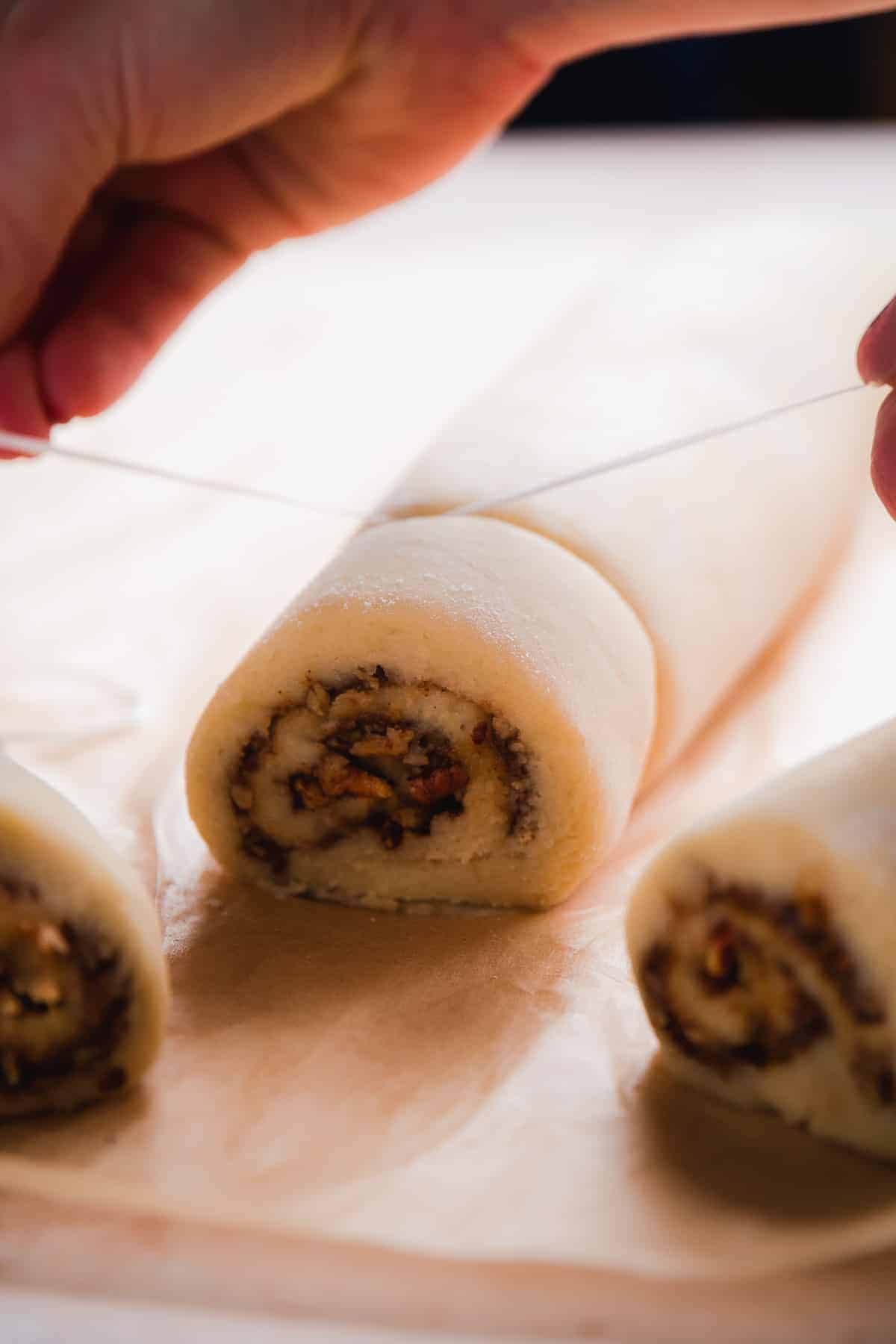 Hand pulling sting to cut dough into cinnamon rolls.