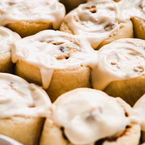 Almond flour cinnamon rolls in a baking dish with icing on top.