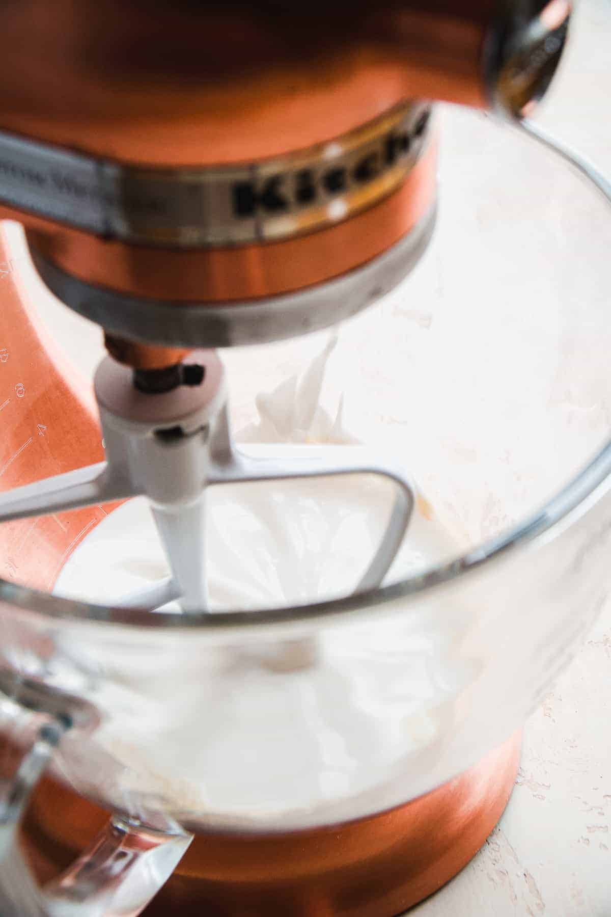 Mixer with a glass bowl mixing milky liquid.