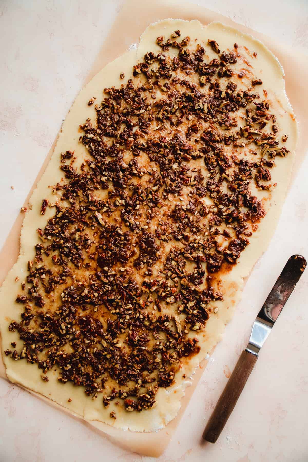 Cinnamon roll dough with filling on top about to be rolled up.