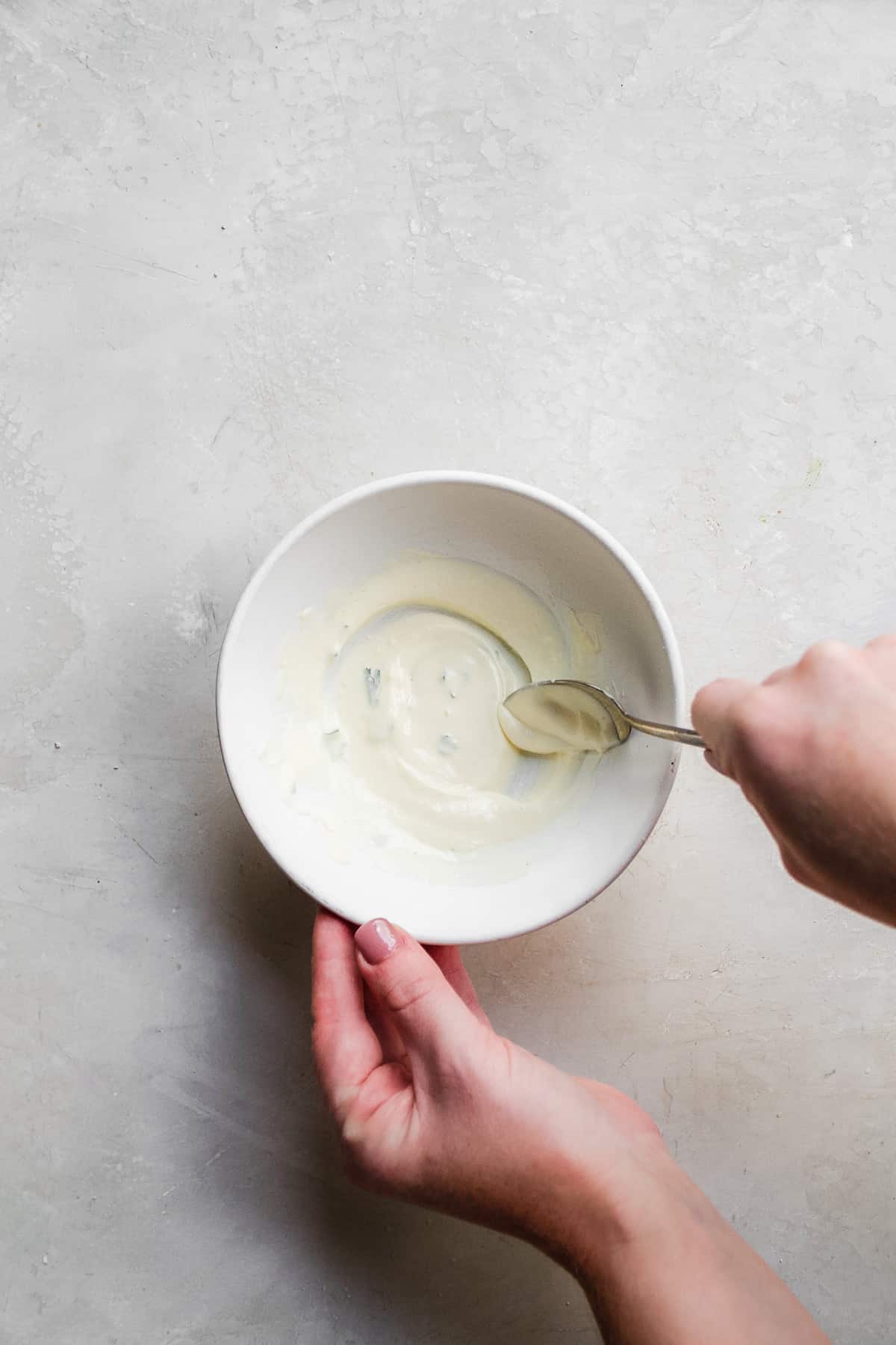 Person whisking sauce in a white bowl.