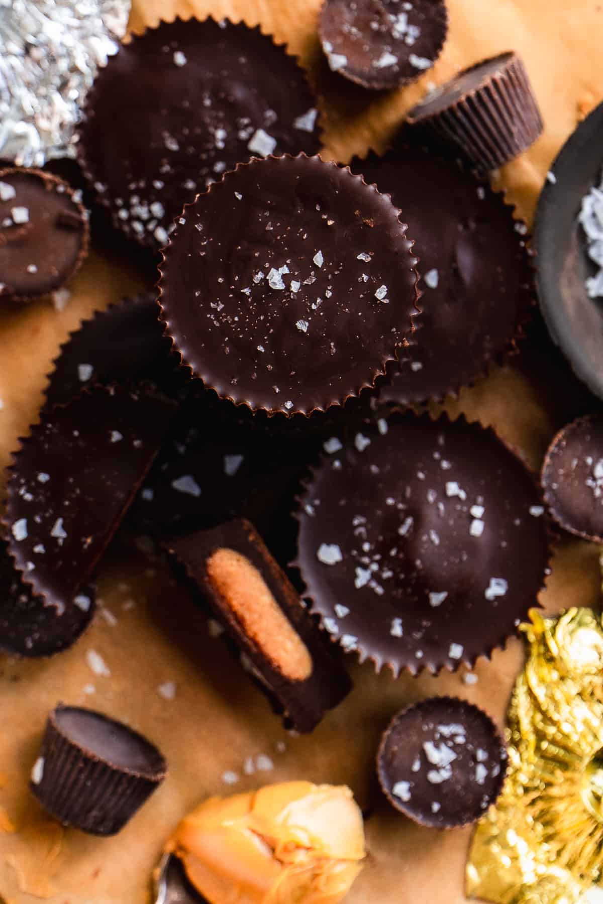 Peanut butter cups scattered on parchment paper with sea salt on top.