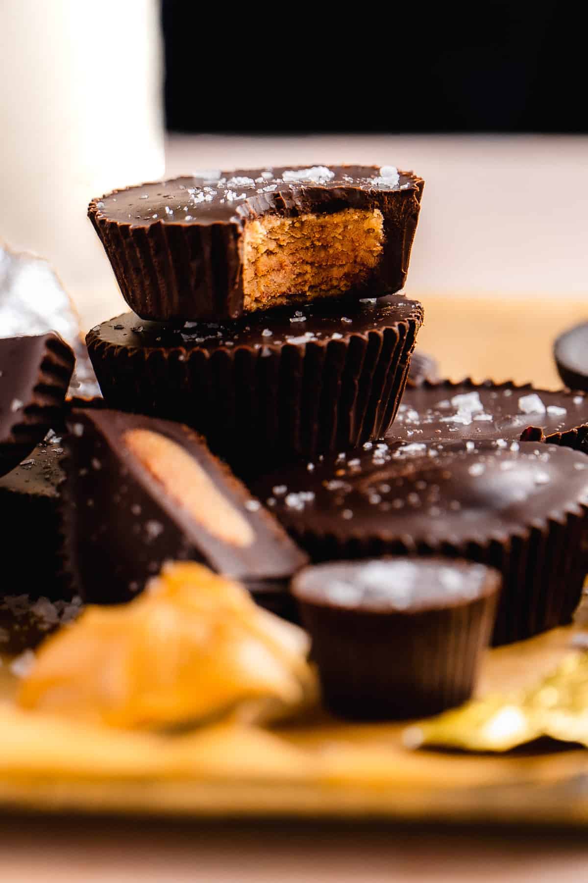 Dark chocolate peanut butter cups stacked on top of one another with sea salt on top.