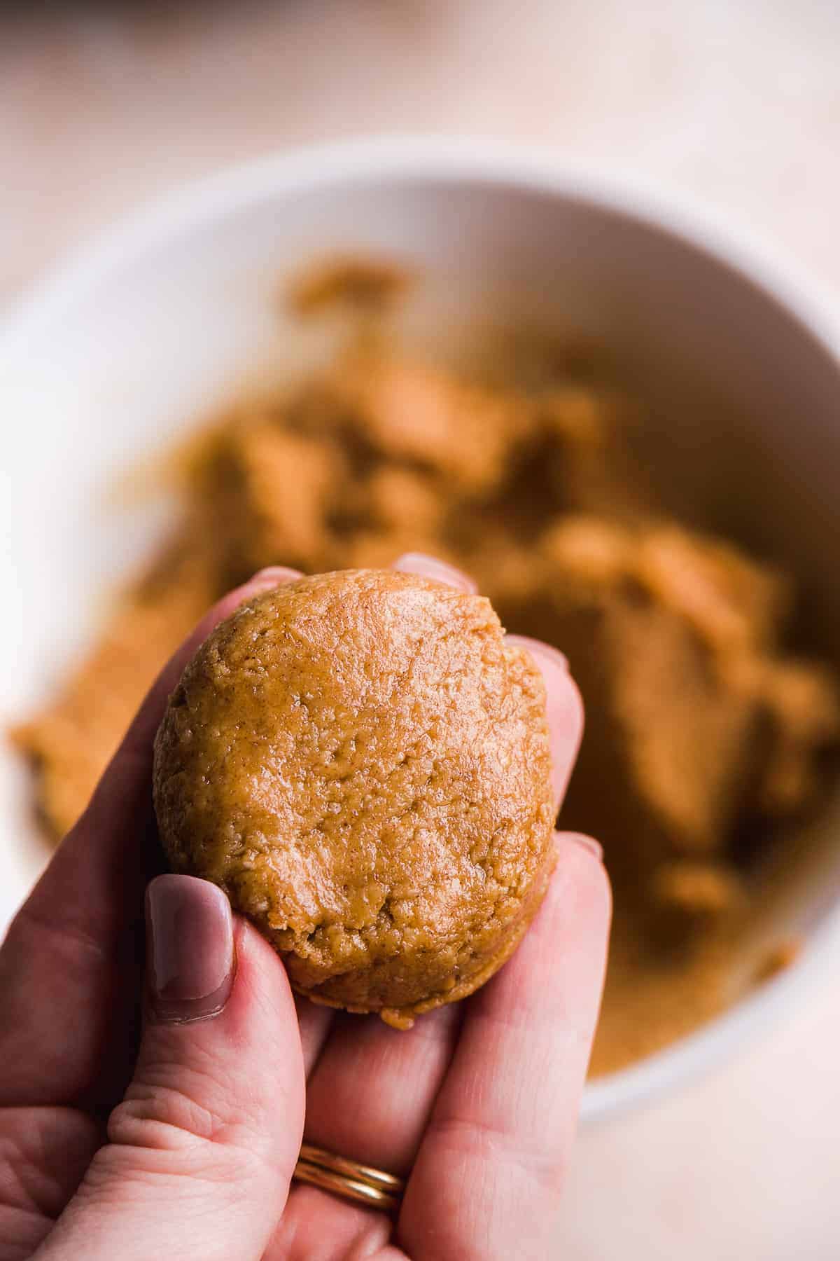 Hand holding peanut butter mixture shaped into a disk.