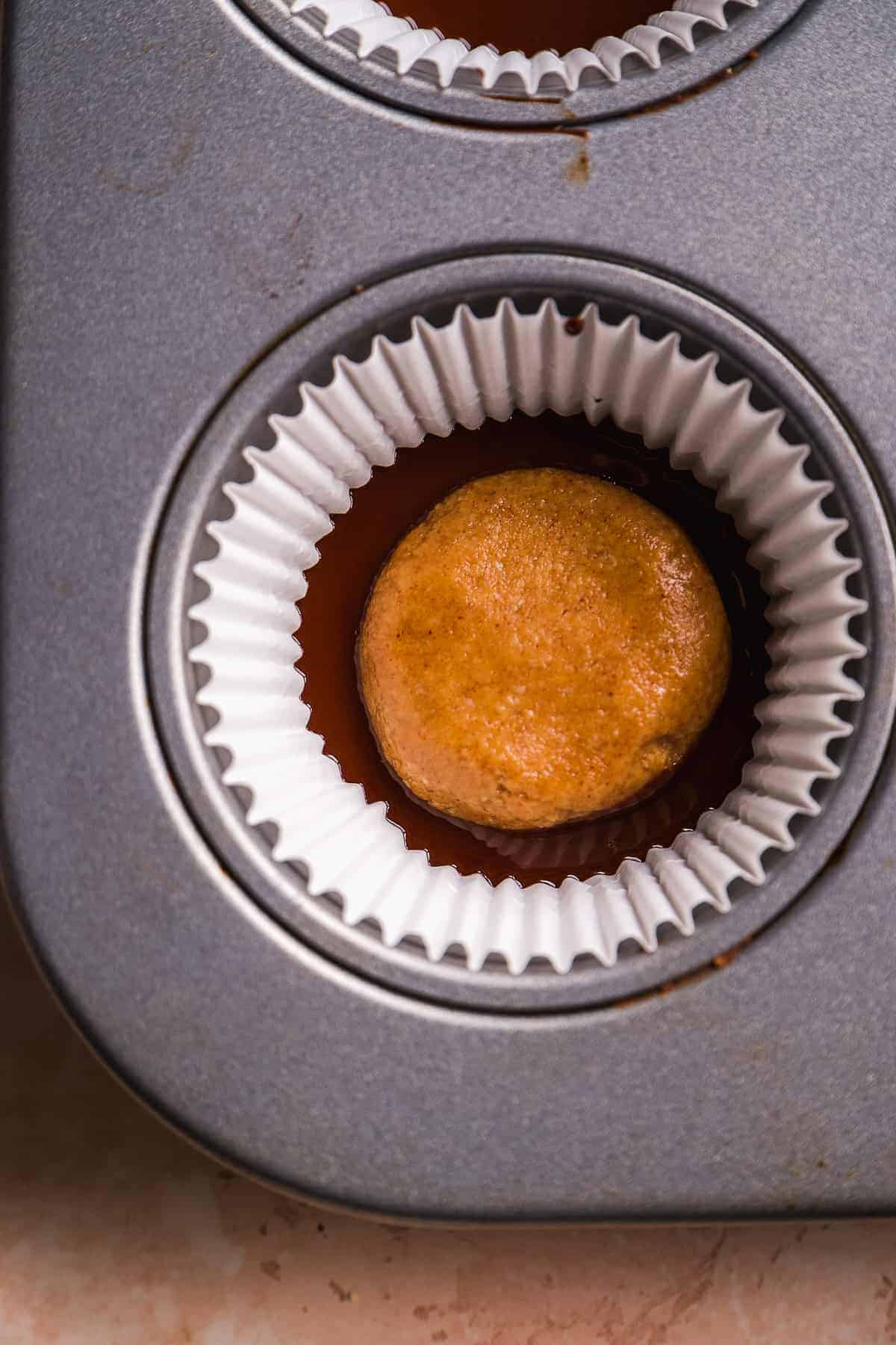 Overhead view of a muffin pan with liners and chocolate and peanut butter filling inside.