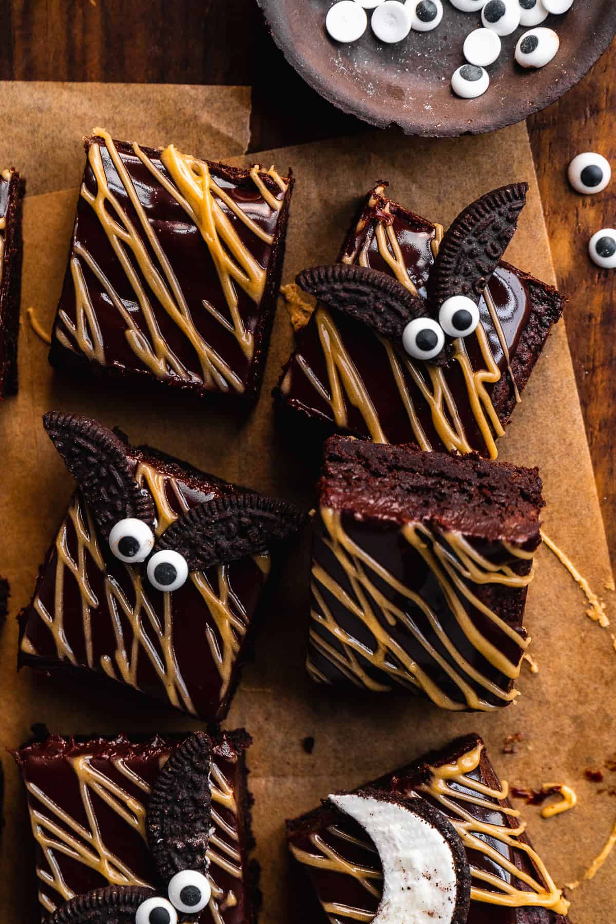 Overhead view of chocolate brownies with almond butter drizzle and Oreo bats on top.