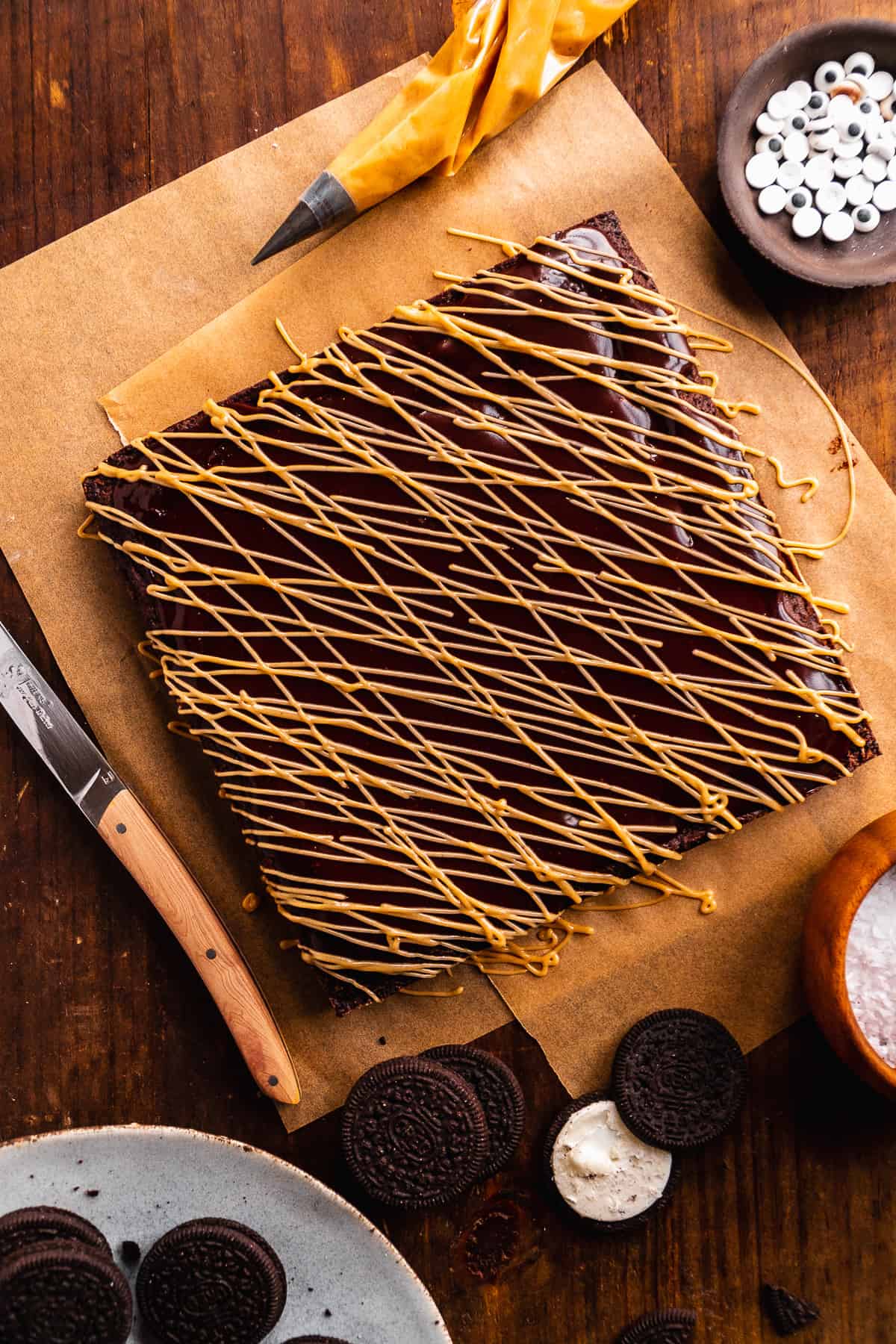 Square brownies with almond butter drizzled over top on a wooden surface.