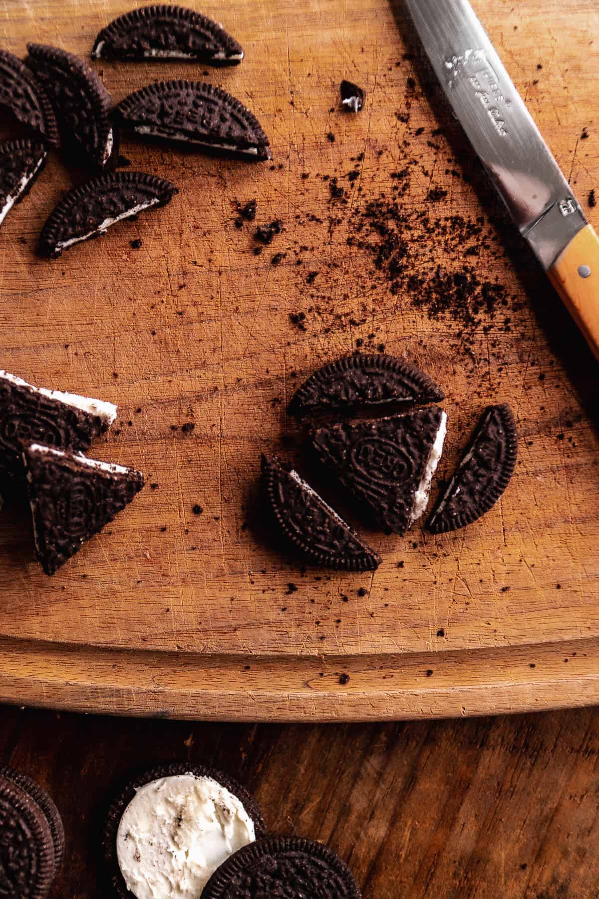 Oreo cut into a triangle on a wooden cutting board.