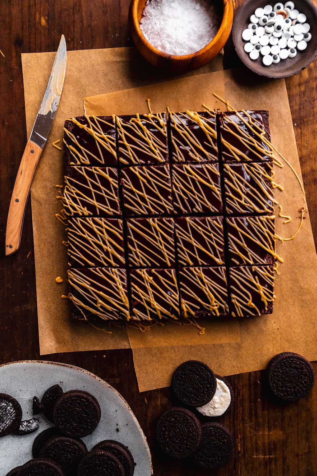 Brownies sliced into squares with almond butter icing drizzled on top on a wooden surface.