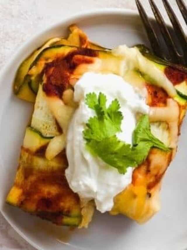 White plate with a zucchini wrapped chicken enchilada and a fork off to the side.