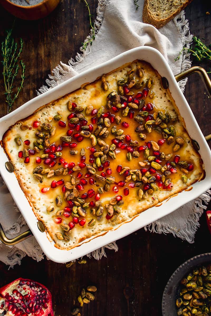 Overhead view of a baked ricotta dish with pistachios and pomegranates.