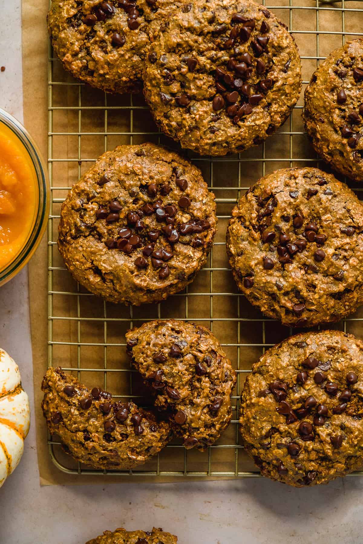 Overhead view of pumpkin cookies on a wire rack with chocolate chips on top.