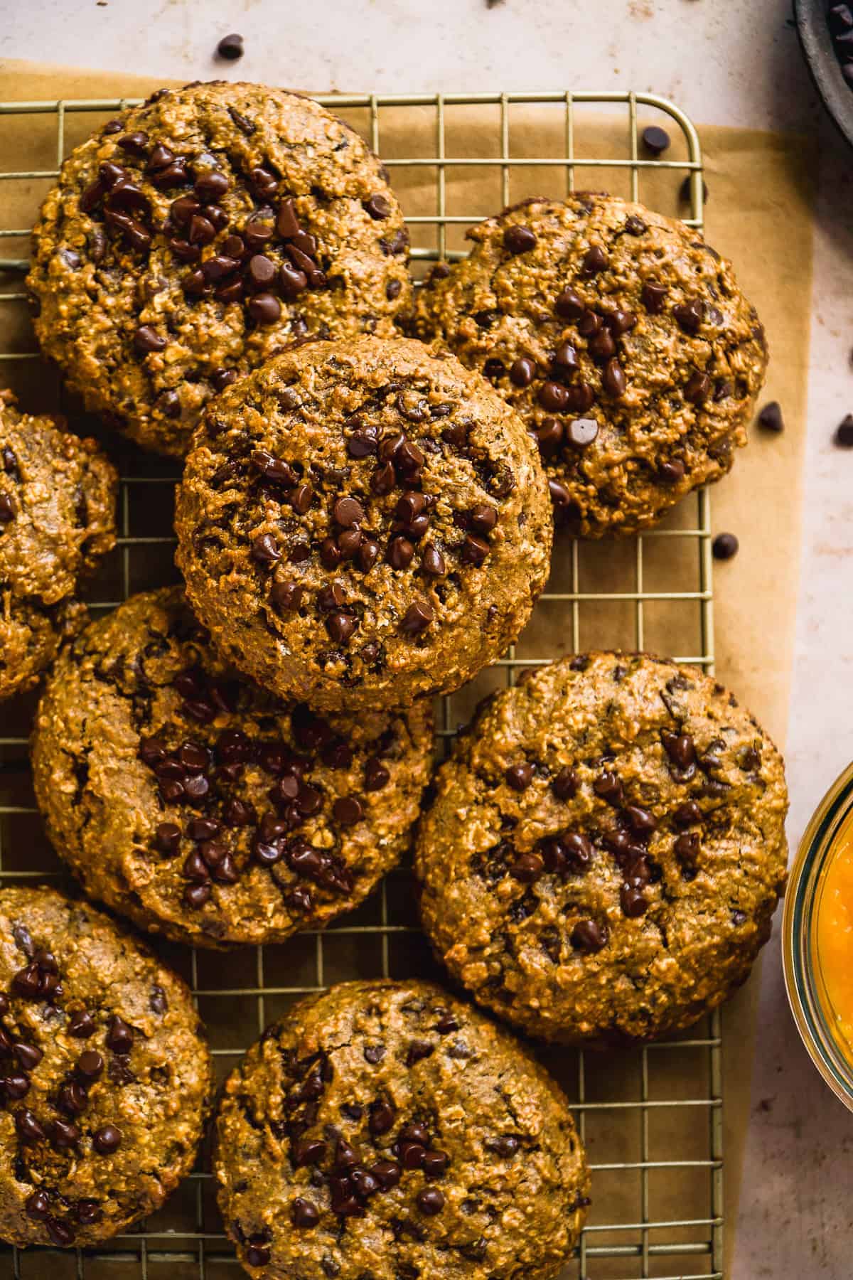 Gluten free pumpkin cookies with chocolate chips scattered on a wire rack.