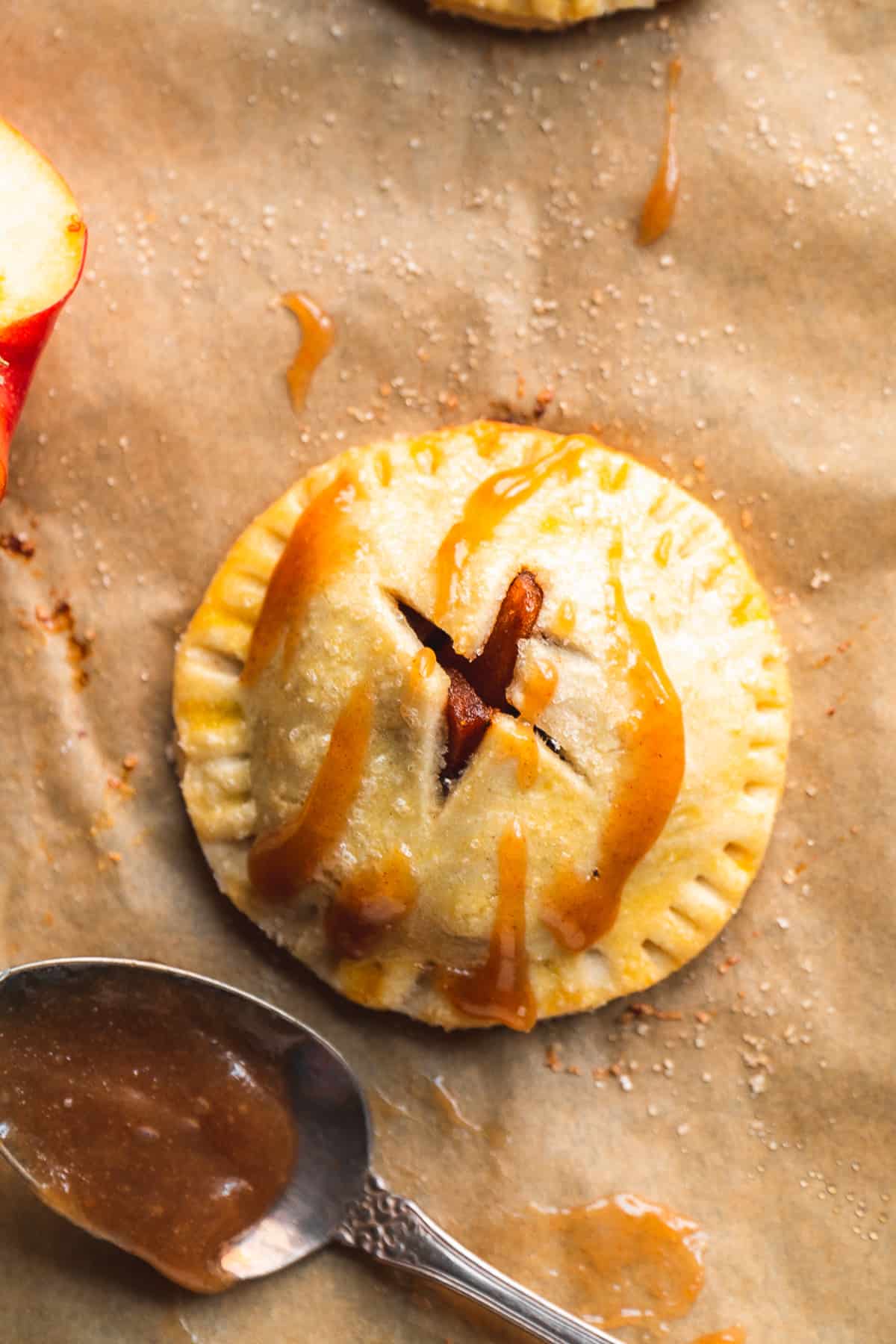 Up close view of a mini apple pie with caramel sauce on top.
