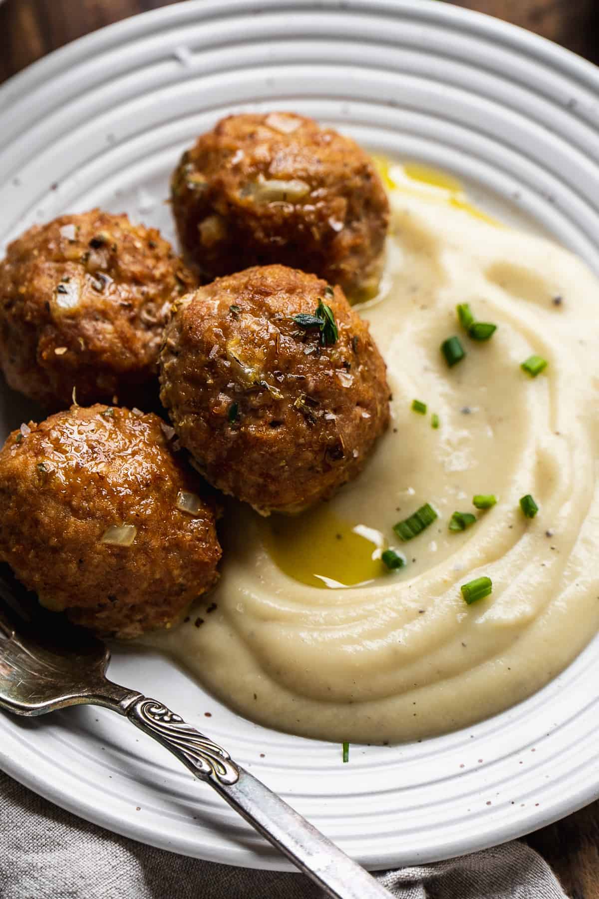 Paleo turkey meatballs on a plate with mashed cauliflower.