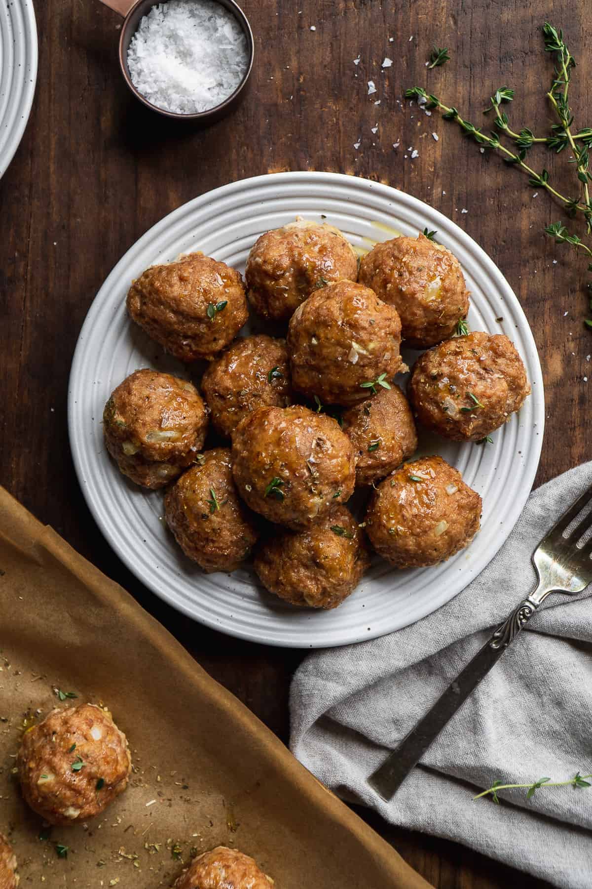 Overhead view of turkey meatballs on a plate on a wooden surface.