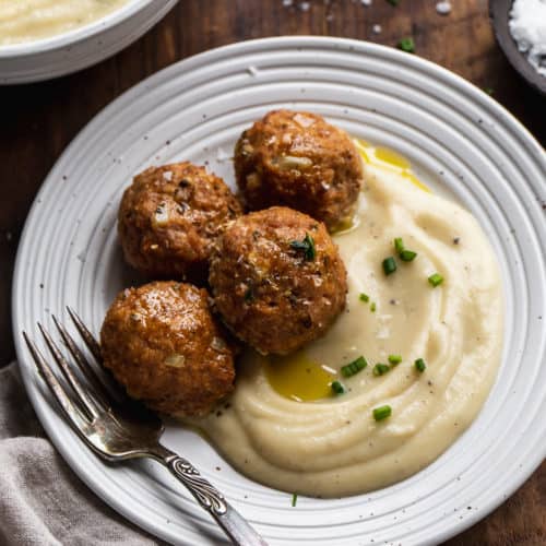Plate with turkey meatballs and mashed cauliflower and a fork on the side.