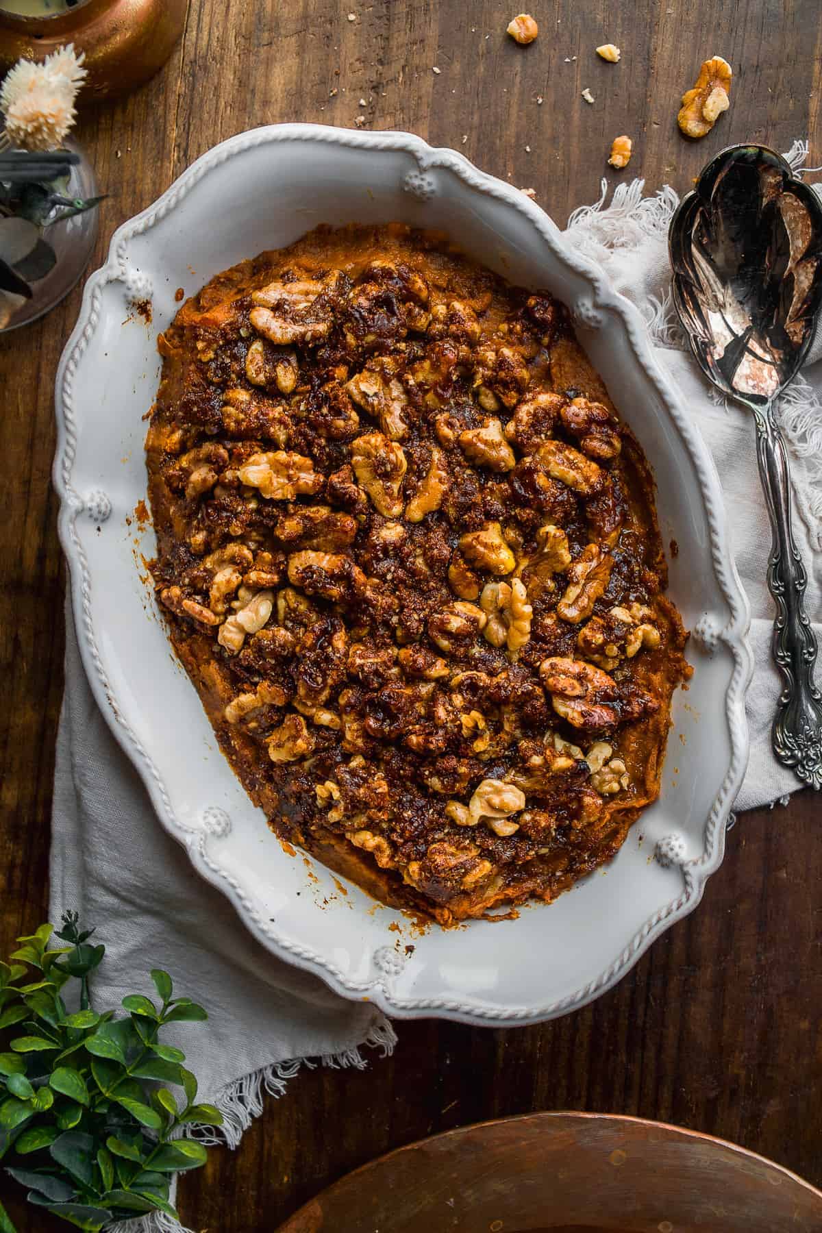 Sweet potato casserole with walnuts on top and a spoon off to the side.