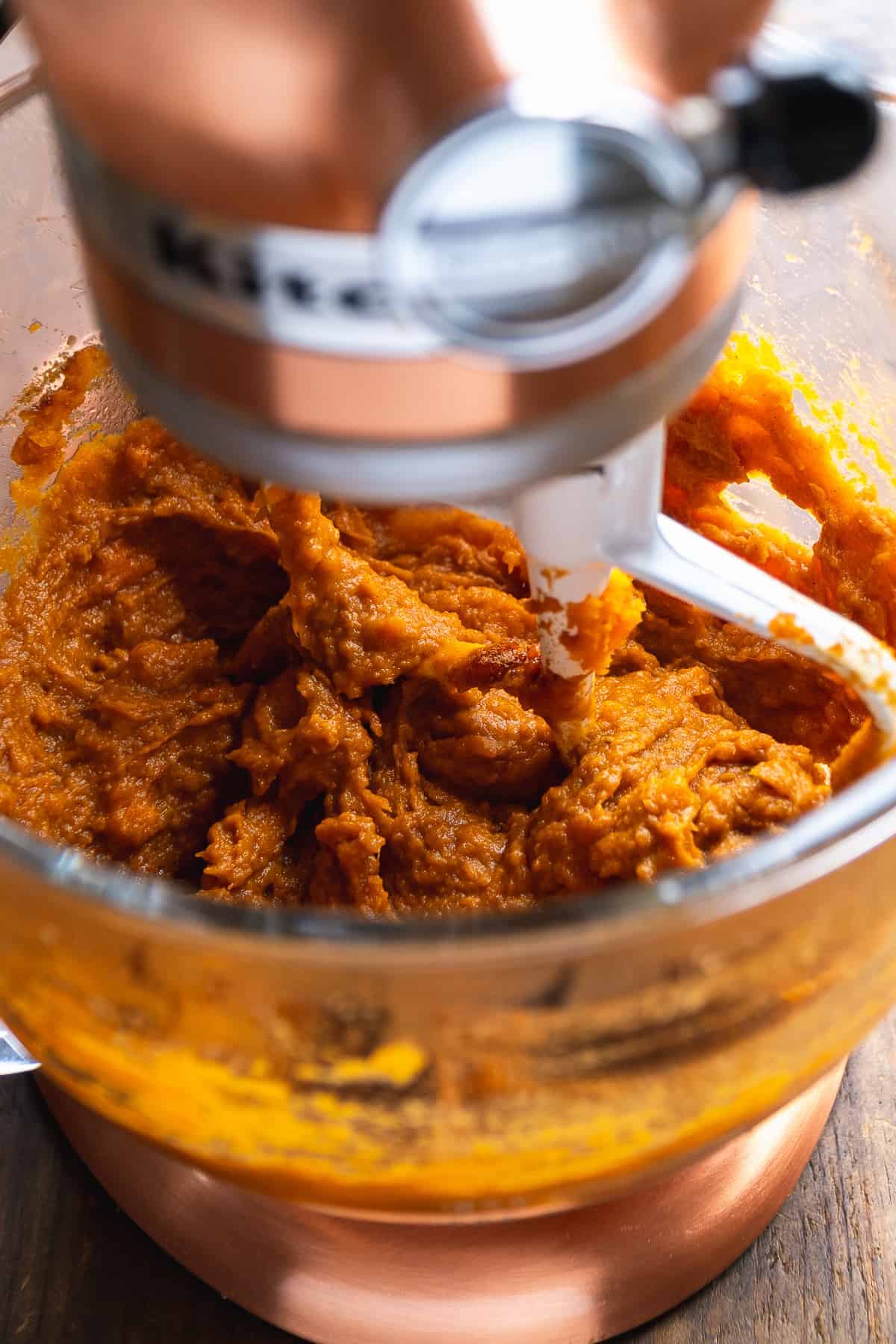 Sweet potatoes being mixed in a mixing bowl.