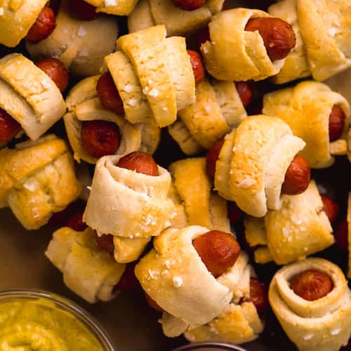 Overhead view of a pile of pigs in a blanket on a platter.