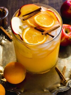 Pitcher of thanksgiving sangria with oranges and cinnamon sticks inside.