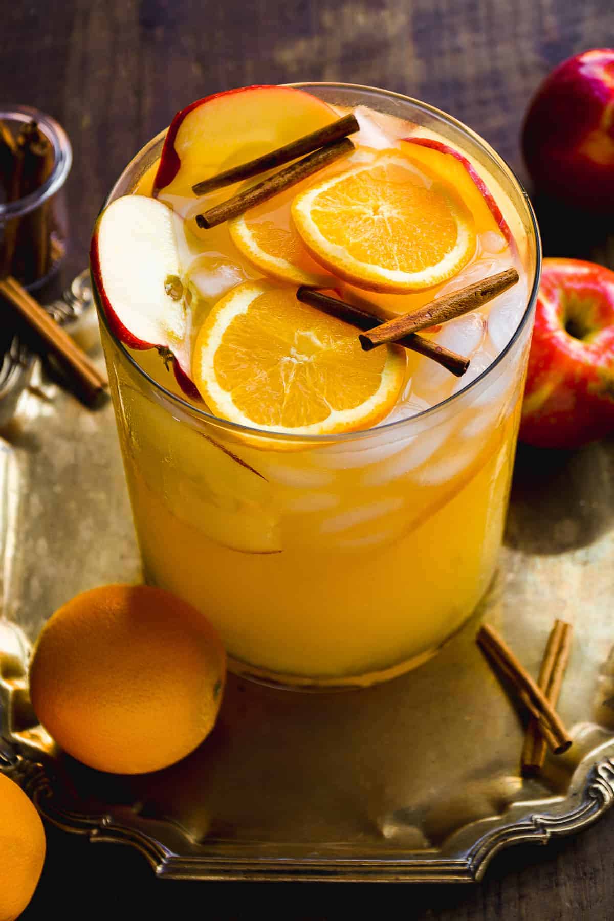 Pitcher of white wine sangria with orange and apple slices on top.