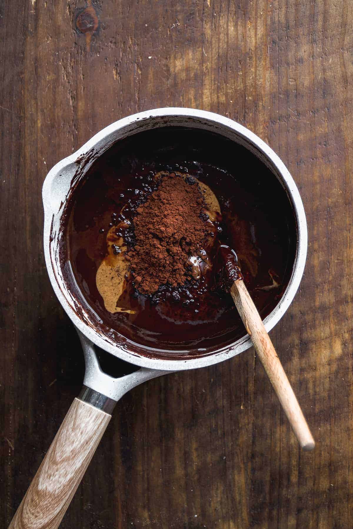 Overhead view of a pot with melted chocolate and cacao powder about to be mixed in.