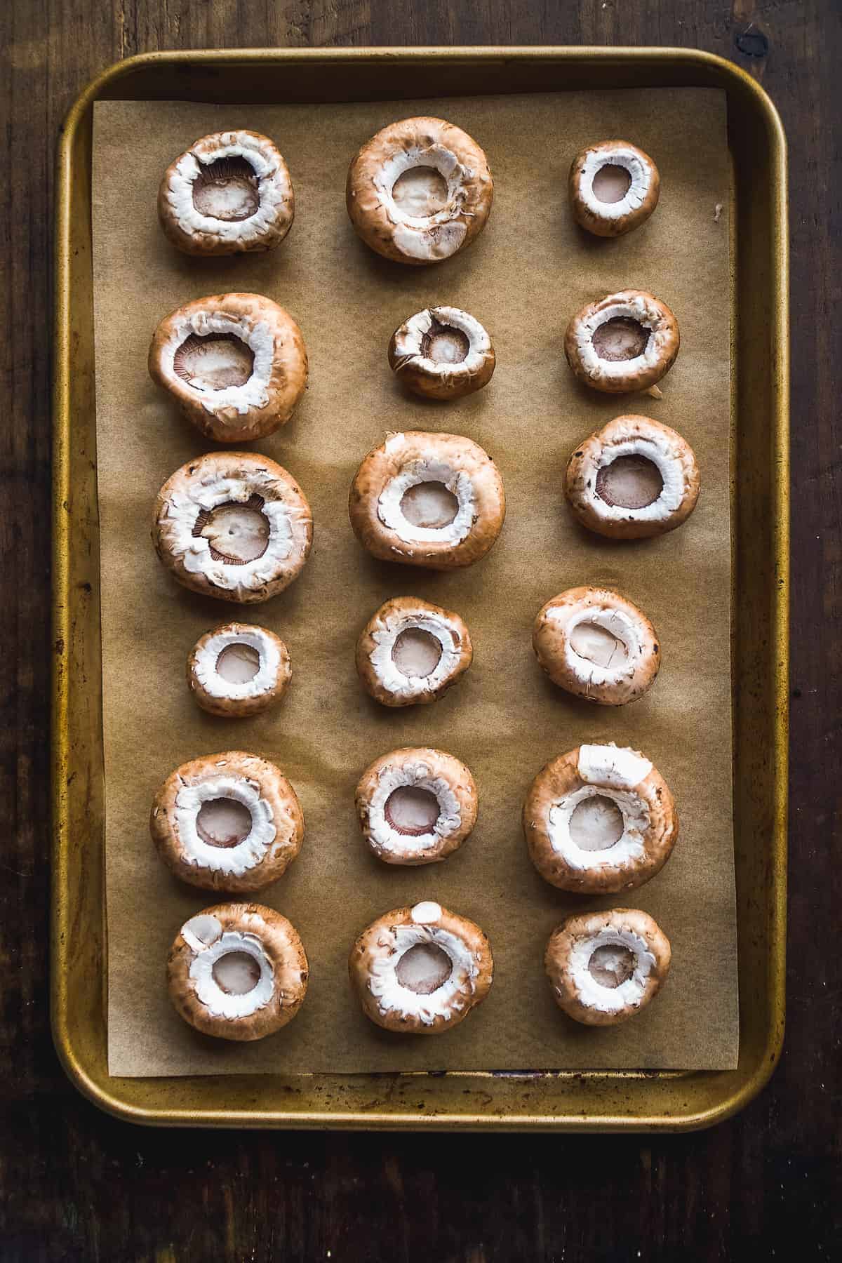 Mushroom caps lined up on a baking sheet.