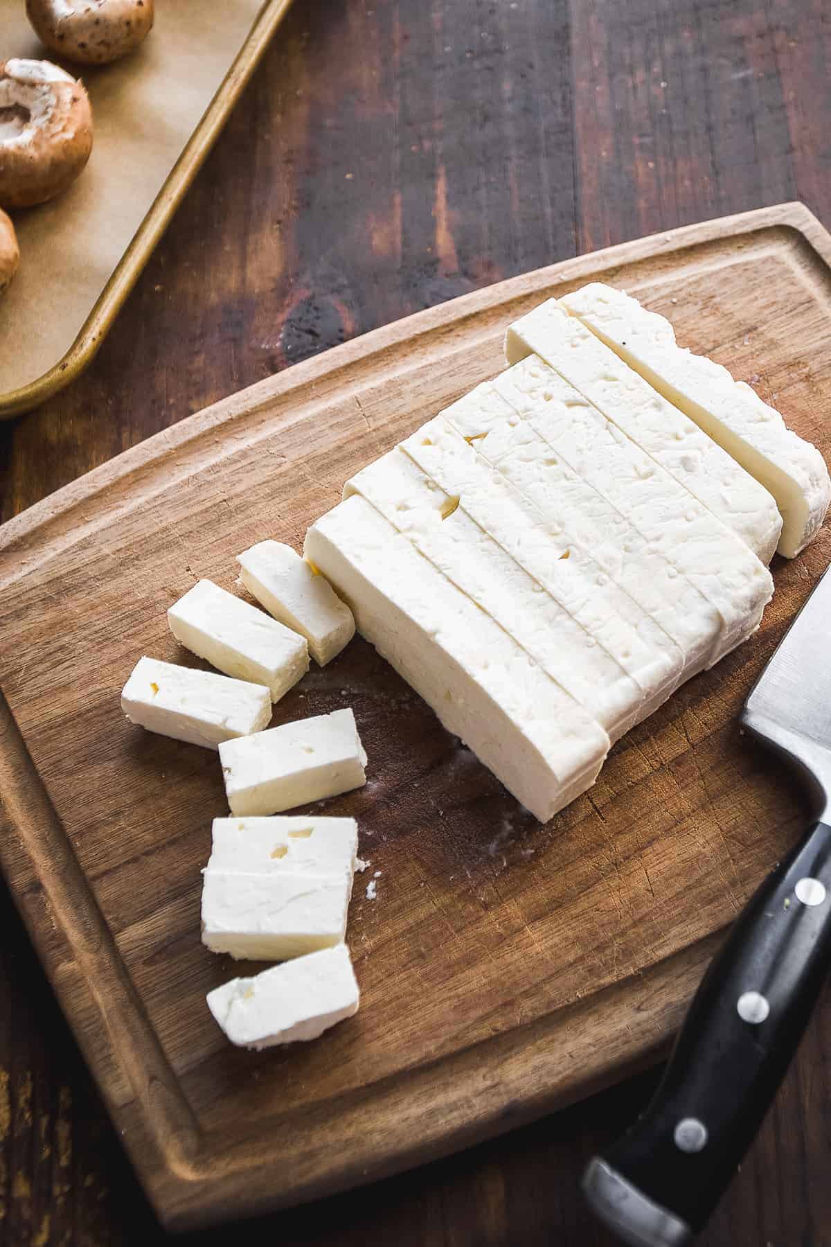 Block of feta cheese on a wooden surface with a knife.