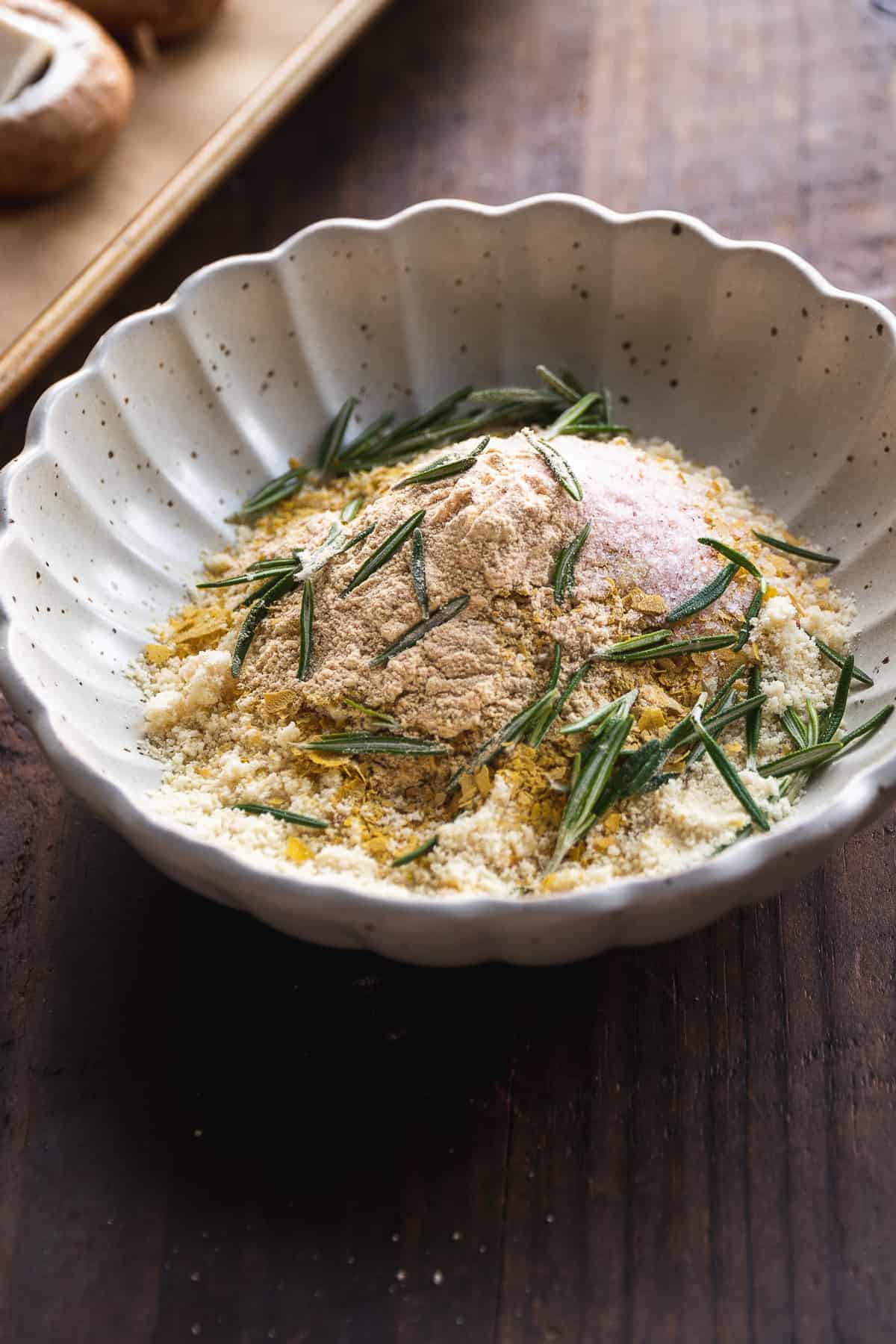 Bread crumbs mixed in a bowl with rosemary stems.