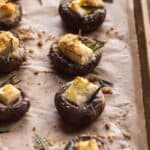 Gluten free stuffed mushrooms in a line on a baking sheet.