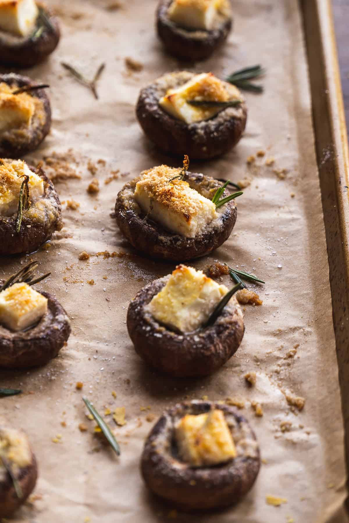 Gluten free stuffed mushrooms in a row on a baking sheet.