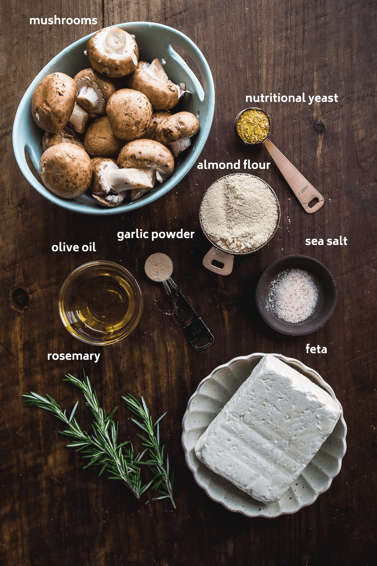 Stuffed mushrooms ingredients on a wooden surface with labels in white.