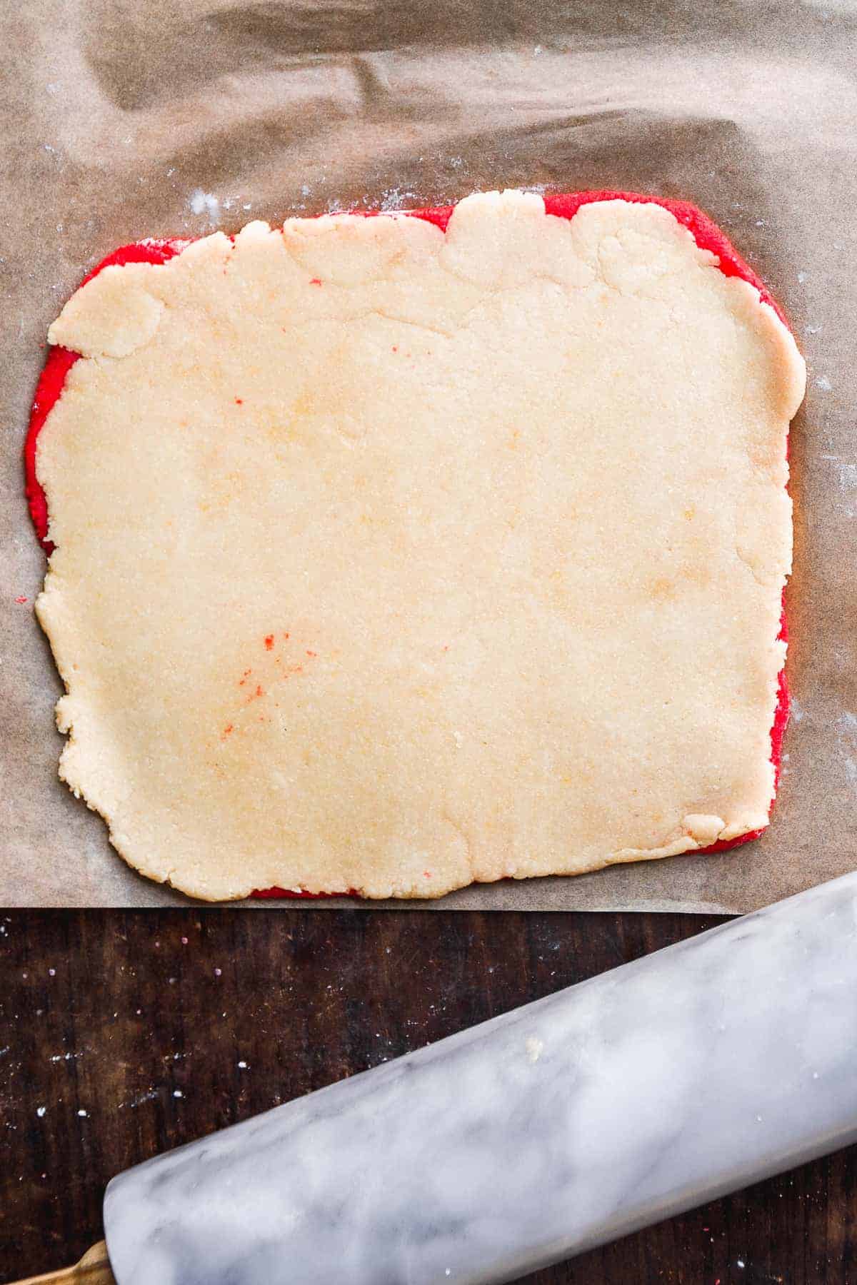 Red and white cookie dough on top of one another about to be rolled.