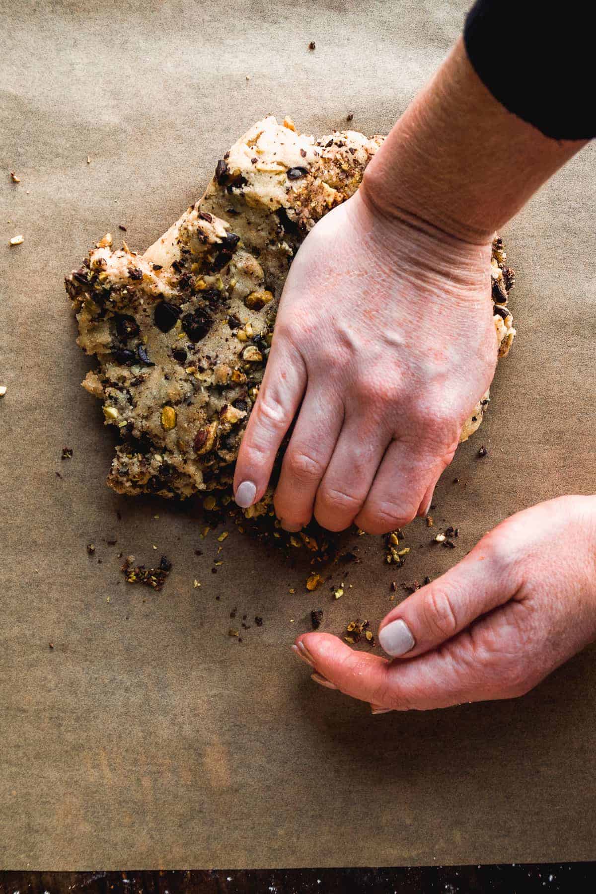 Person kneading cookie dough with hands.