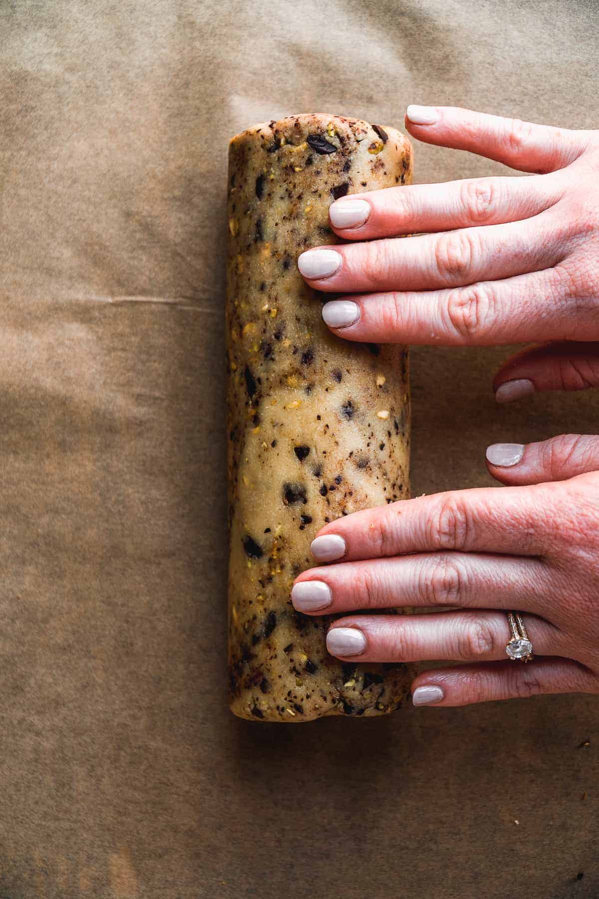 Person rolling cookie dough into a log.