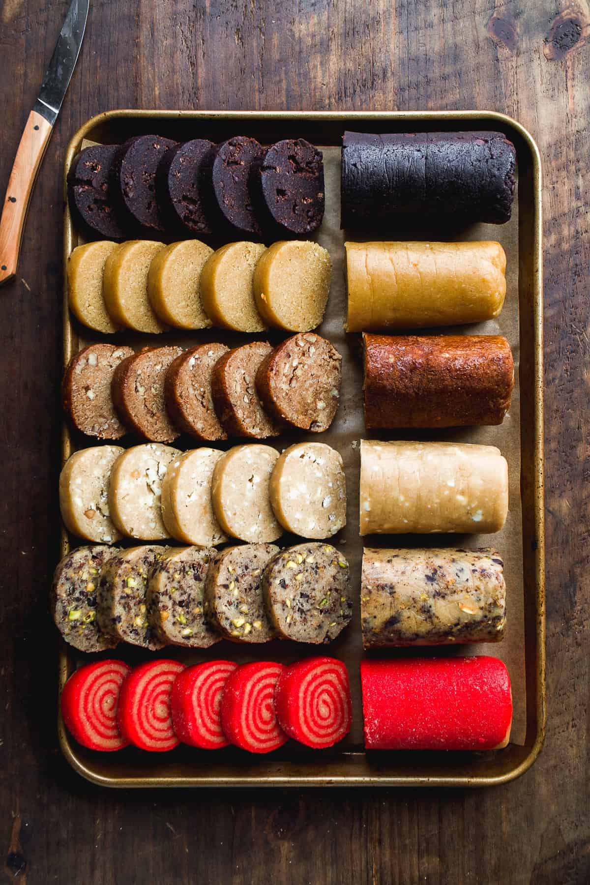 Line of slice and bake cookie dough logs on a gold tray.